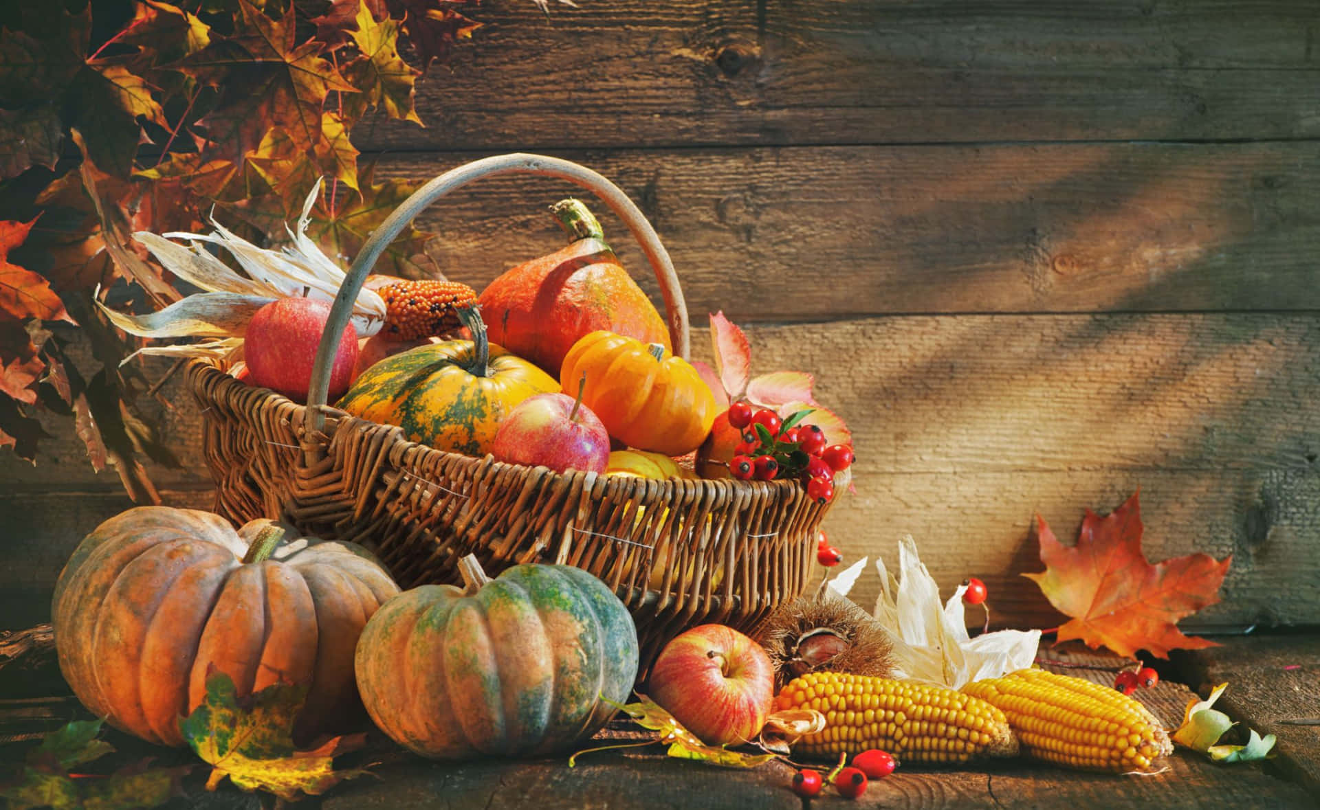 a basket of pumpkins and corn on a wooden table