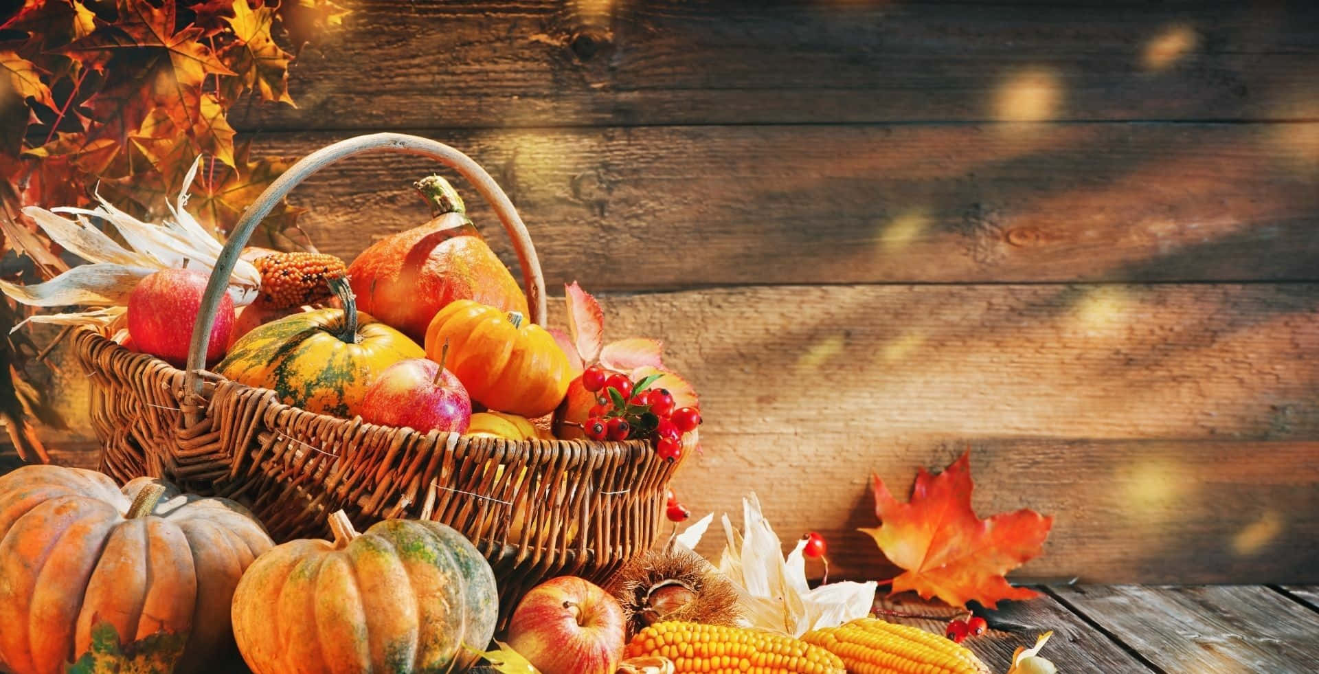 A Basket Of Pumpkins And Fall Leaves On A Wooden Table Wallpaper