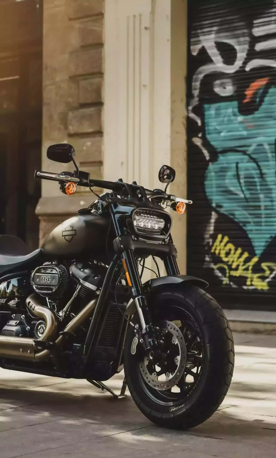 En sort motorcykel parkerede foran et taget dækket med grafitti Wallpaper