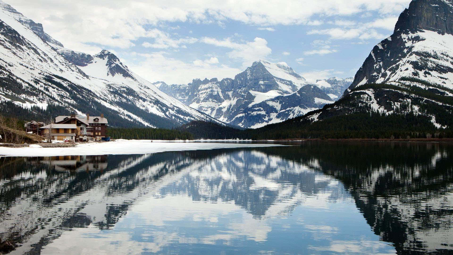 a lake with mountains and a house reflected in it Wallpaper