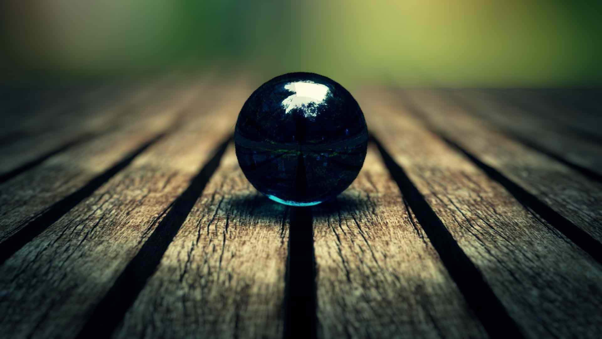 a black ball sitting on top of a wooden table Wallpaper