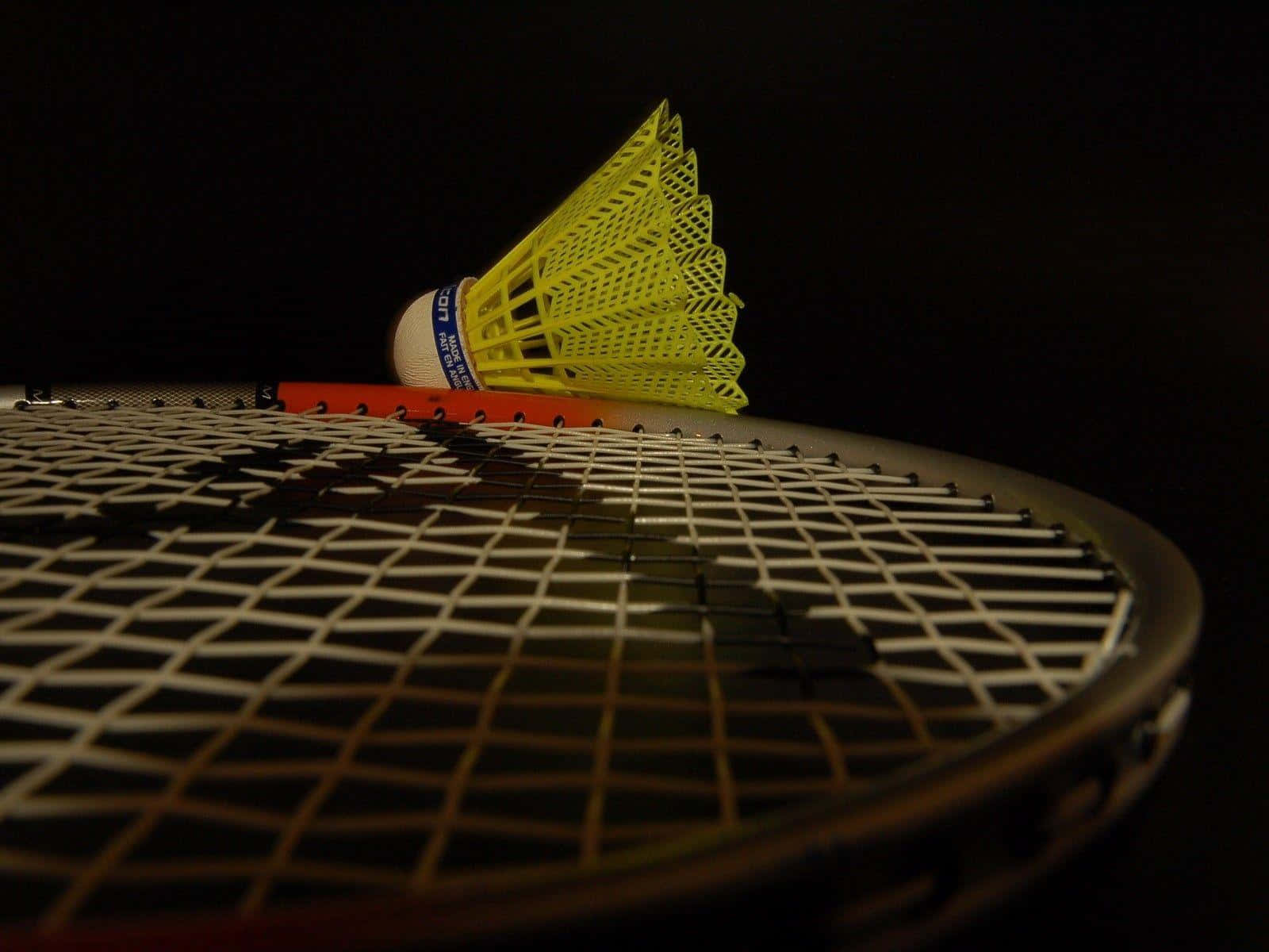 A Badminton Racket With A Yellow Shuttlecock