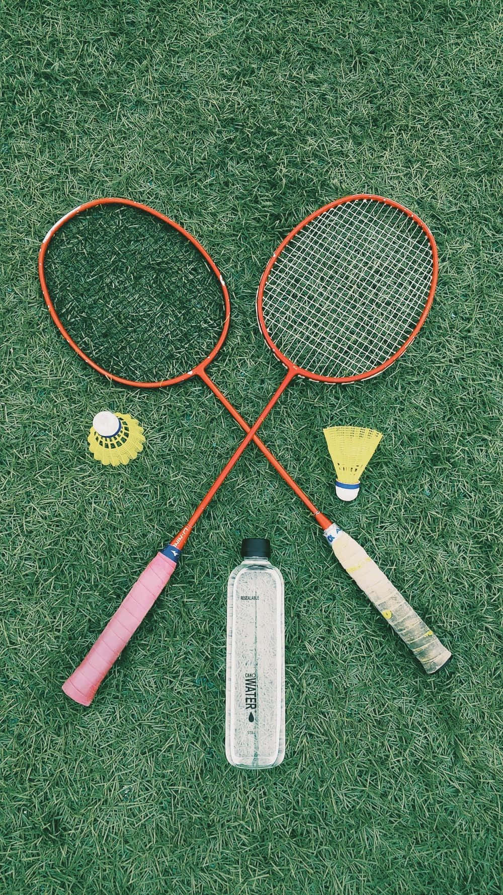 Badminton Rackets And Bottle On Grass