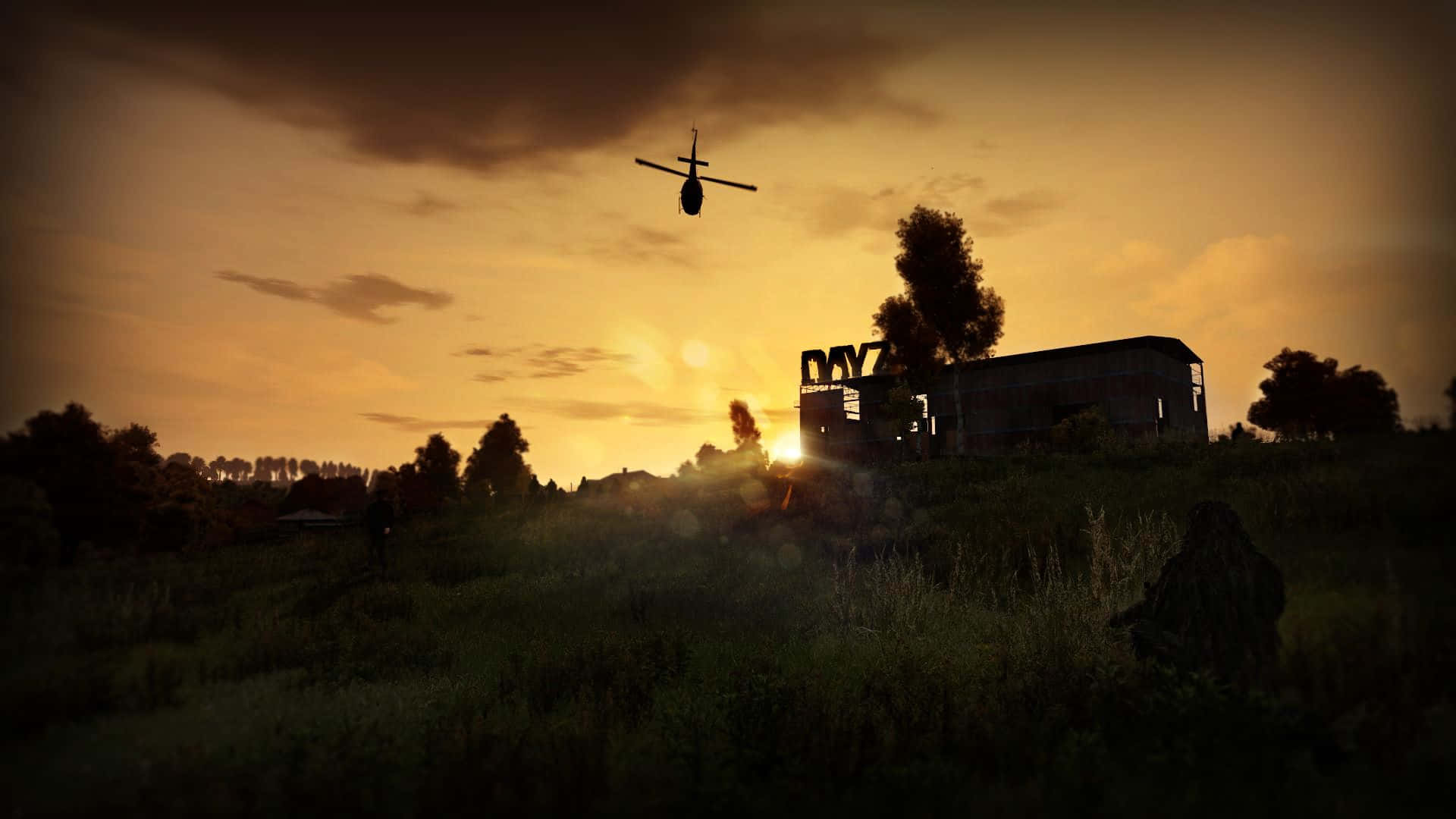 A Helicopter Flying Over A Field At Sunset