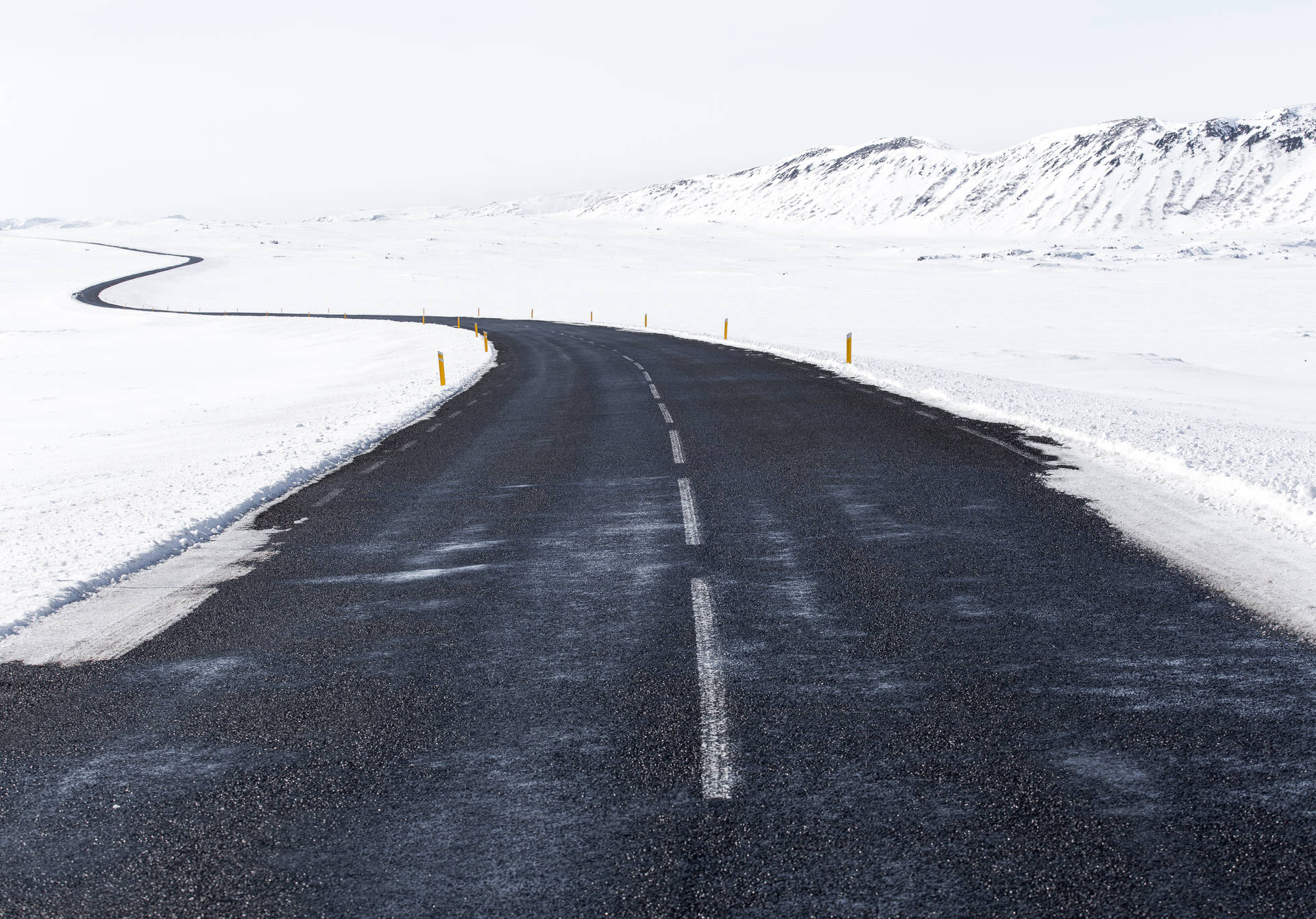 HD Desktop wallpaper of black asphalt road covered in white snow. 