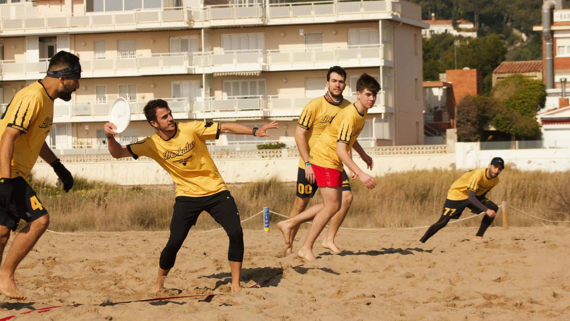 Ungruppo Di Uomini Che Giocano A Frisbee Sulla Spiaggia