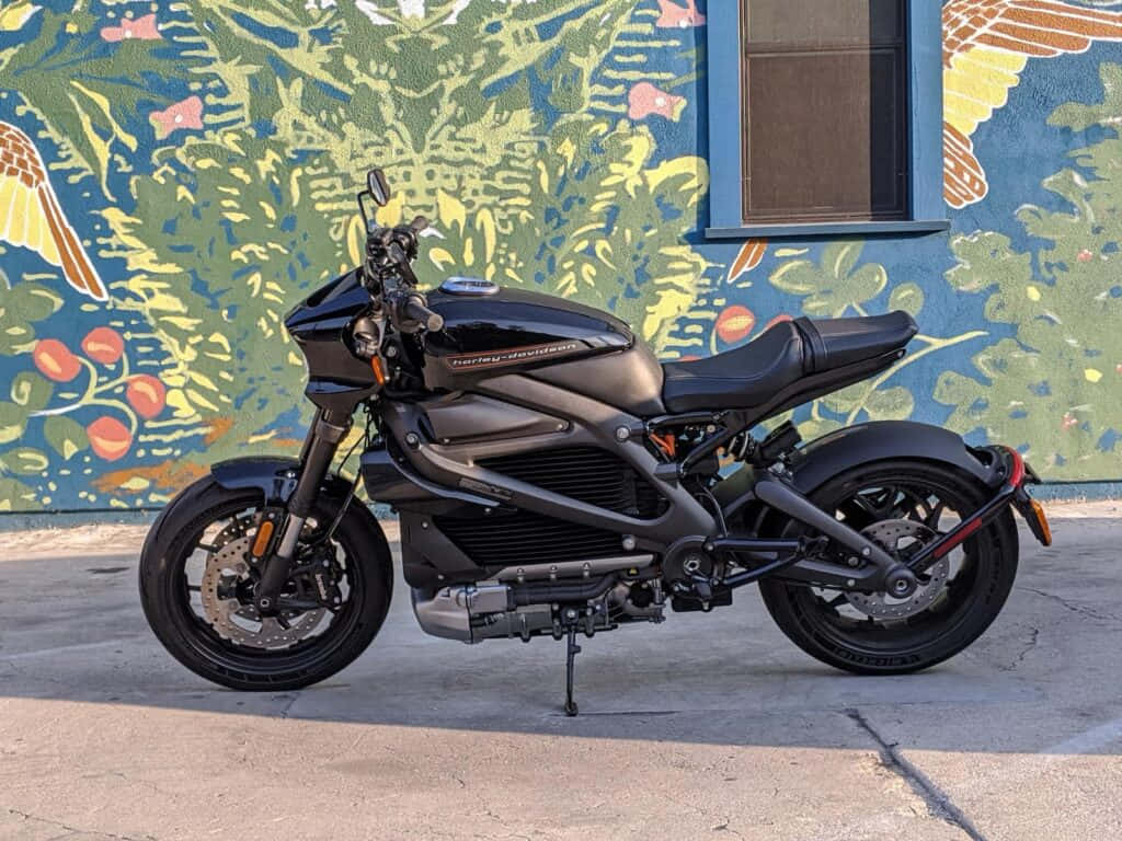 En sort motorcykel parkeret foran et farverigt maleri Wallpaper