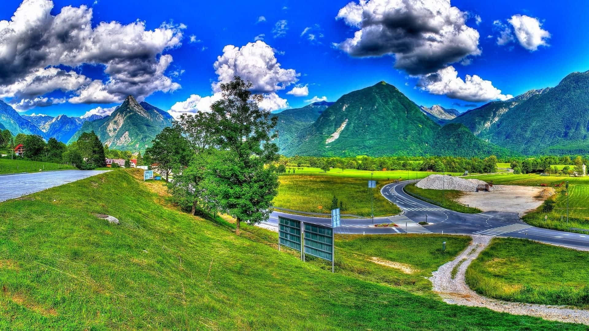 A View Of A Mountain Road And A Green Field