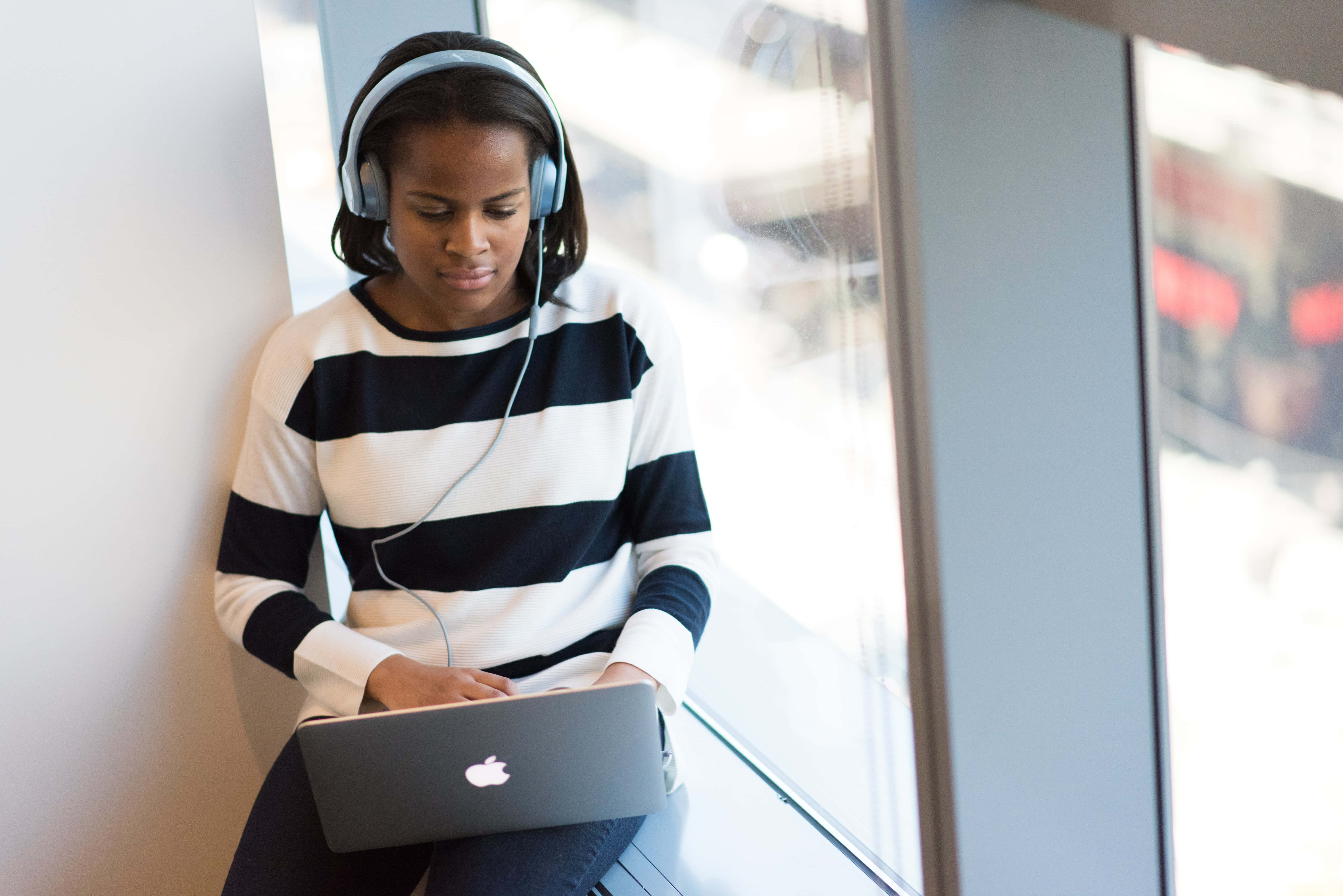 A Woman Wearing Headphones And Using A Laptop Wallpaper