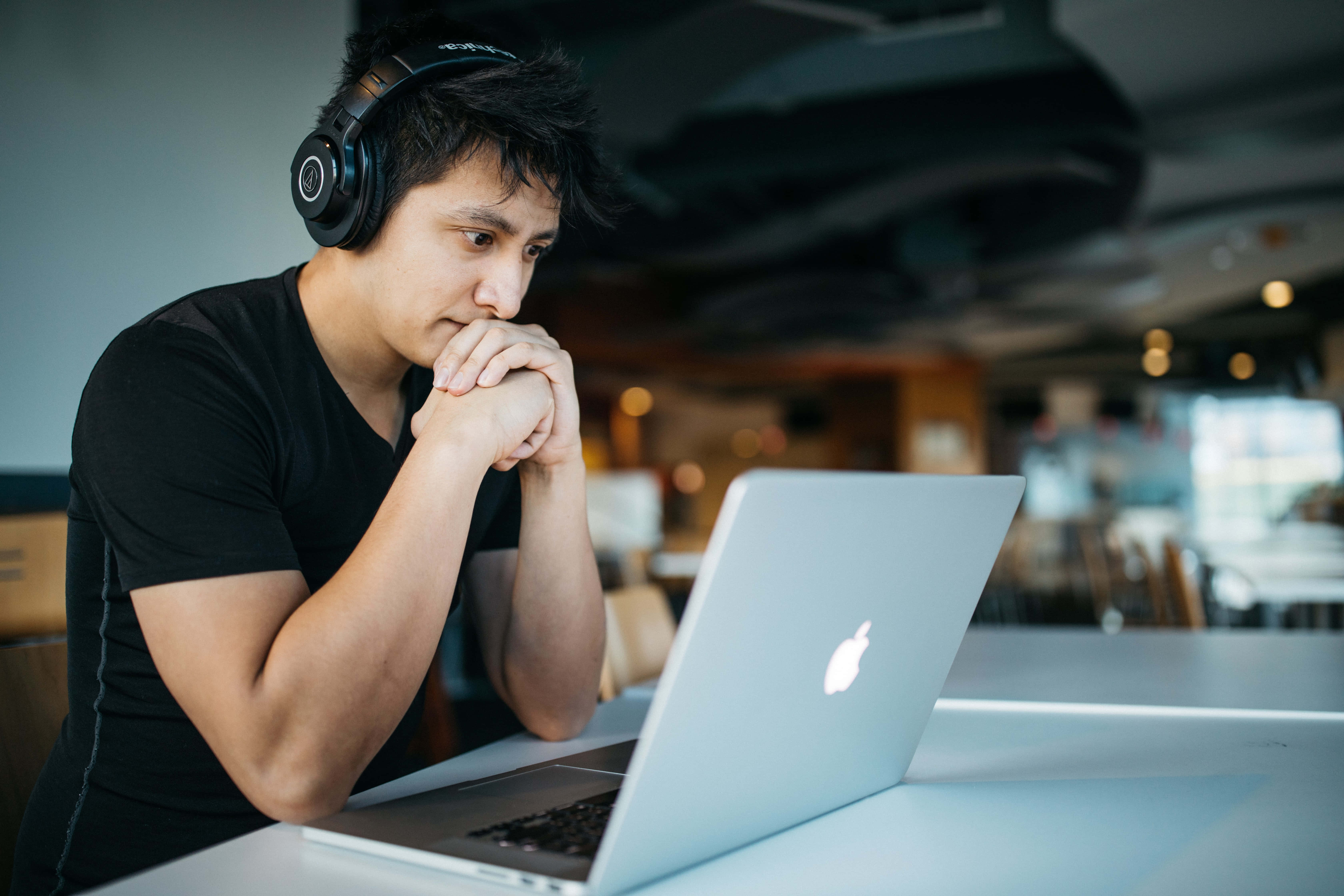 A Man Wearing Headphones Is Sitting At A Table With A Laptop Wallpaper