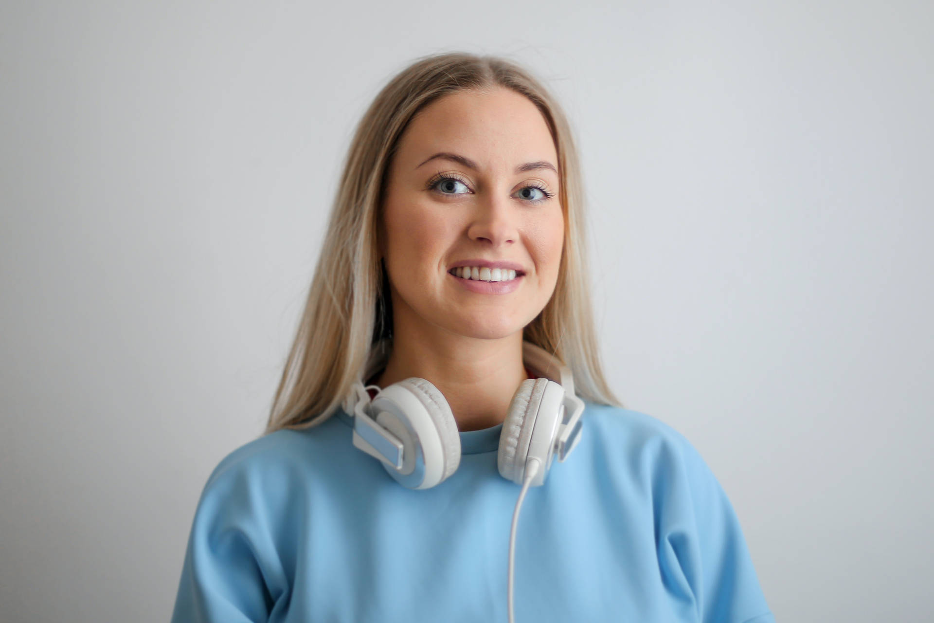 Portræt af pige iført hovedtelefoner og blå top Wallpaper
