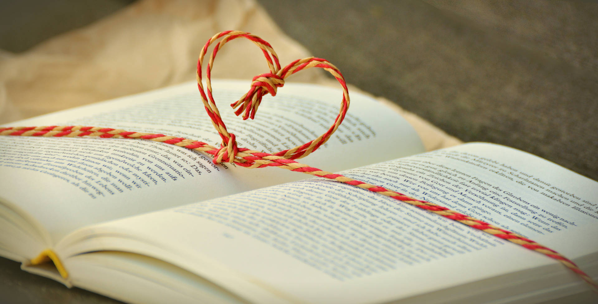 Heart shaped thread knot on a book wallpaper