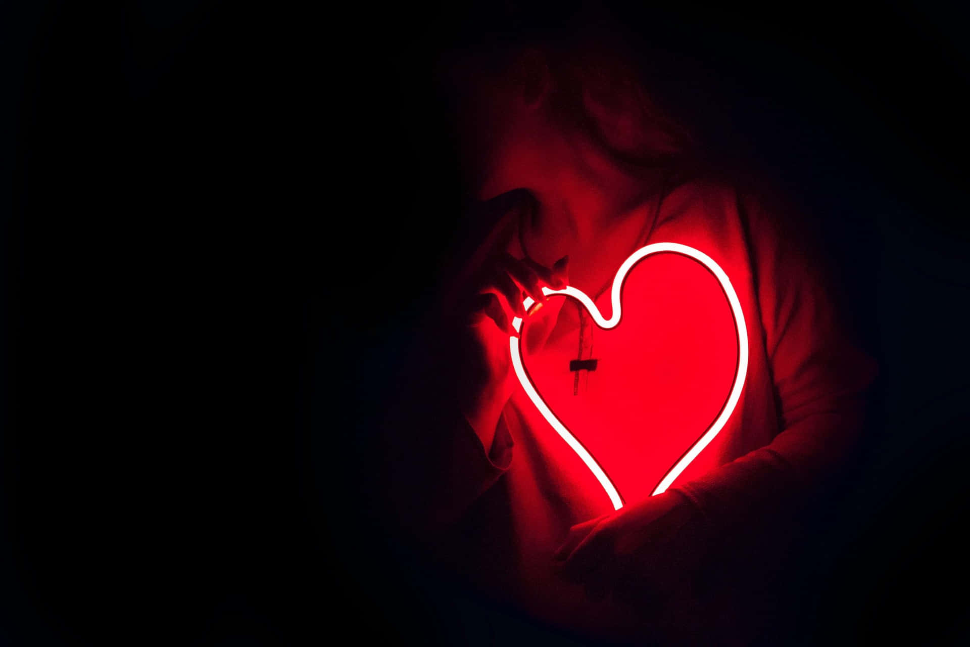 En kvinde, der holder et rødt hjerte i mørket