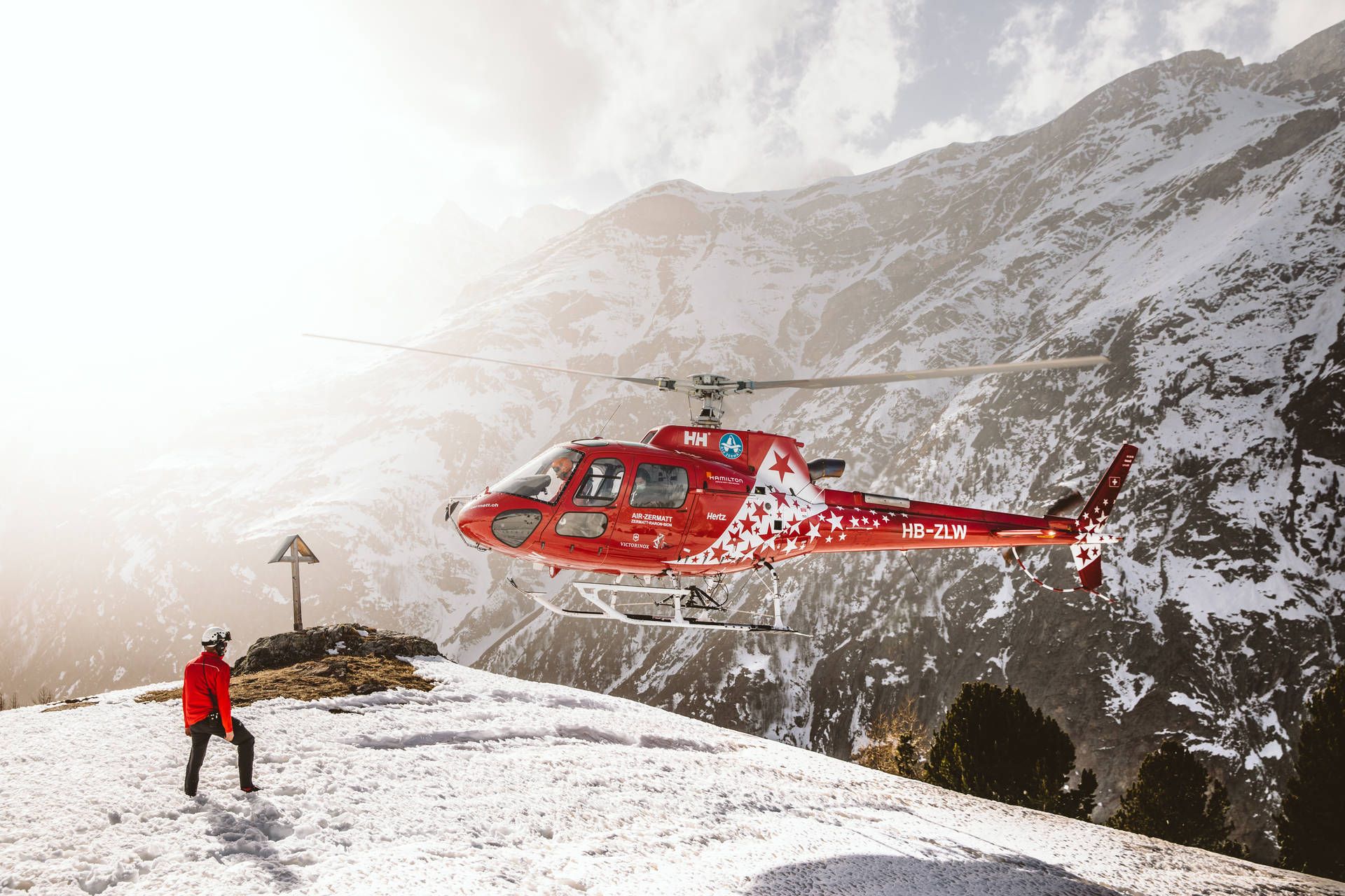 Majestic Helicopter Landing on a Snowy Mountain Peak Wallpaper
