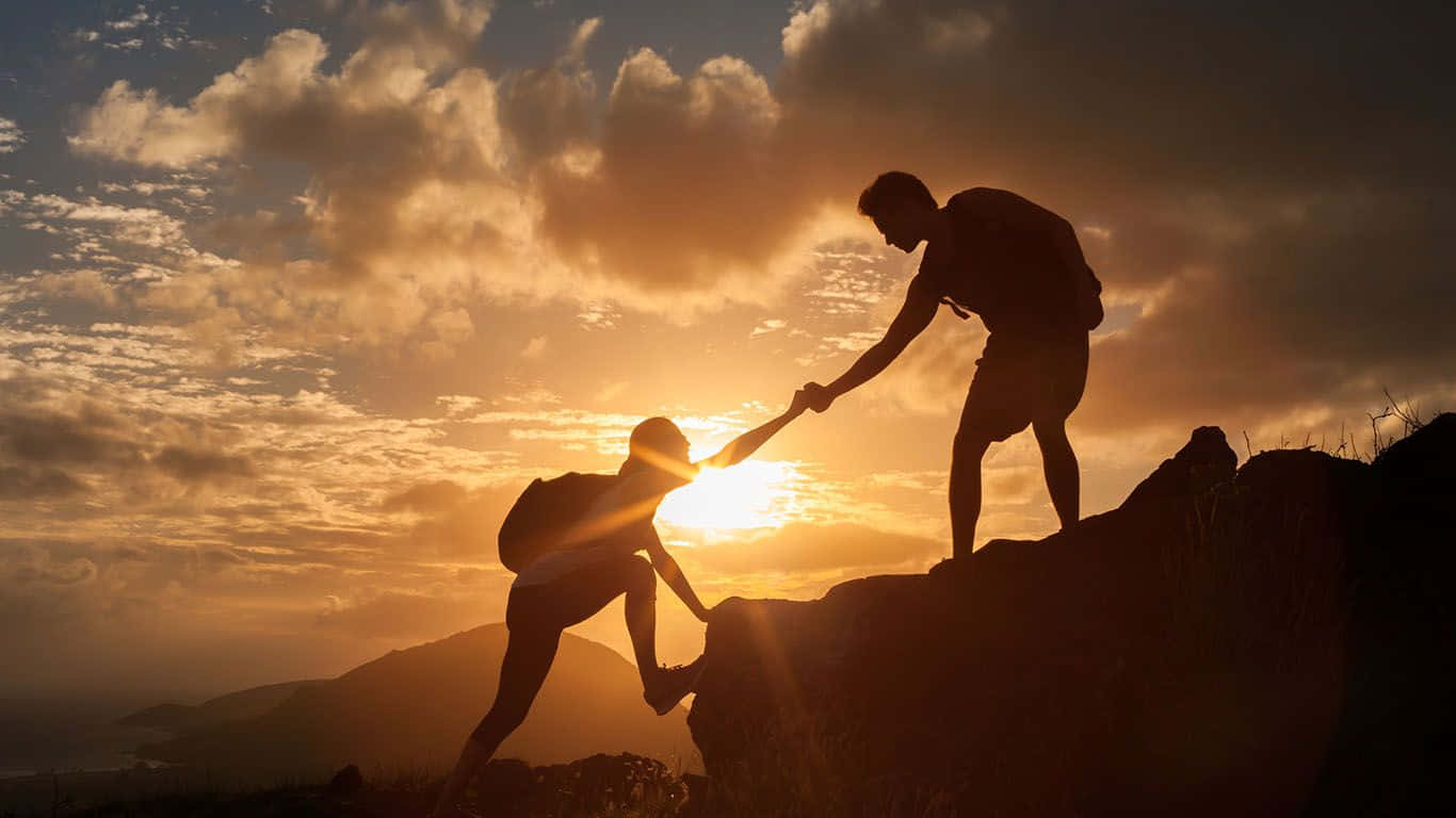 Two People Are Holding Hands On Top Of A Mountain