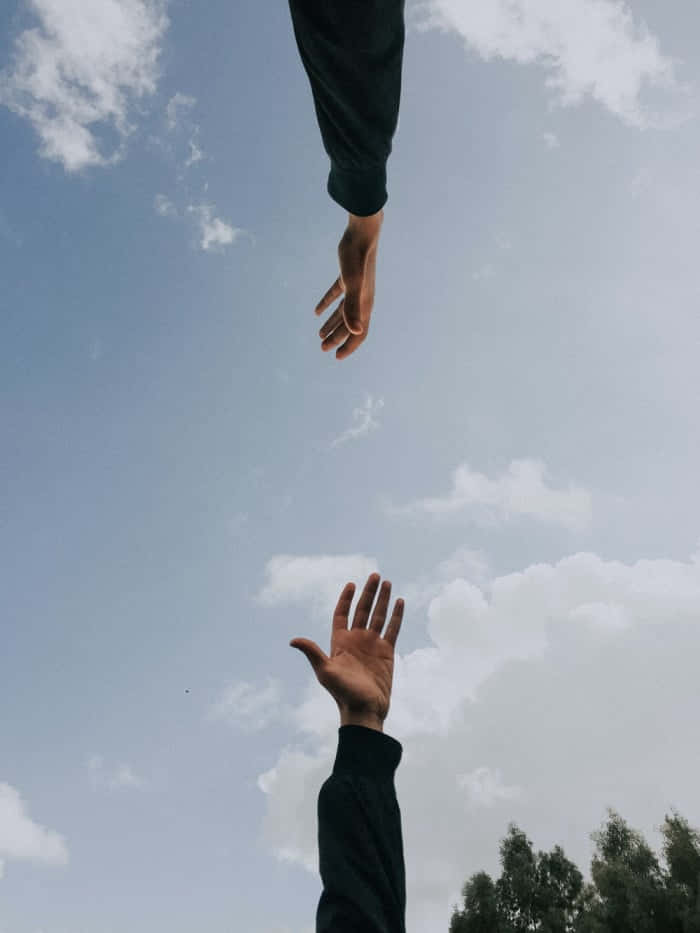Two People Reaching For Something In The Sky