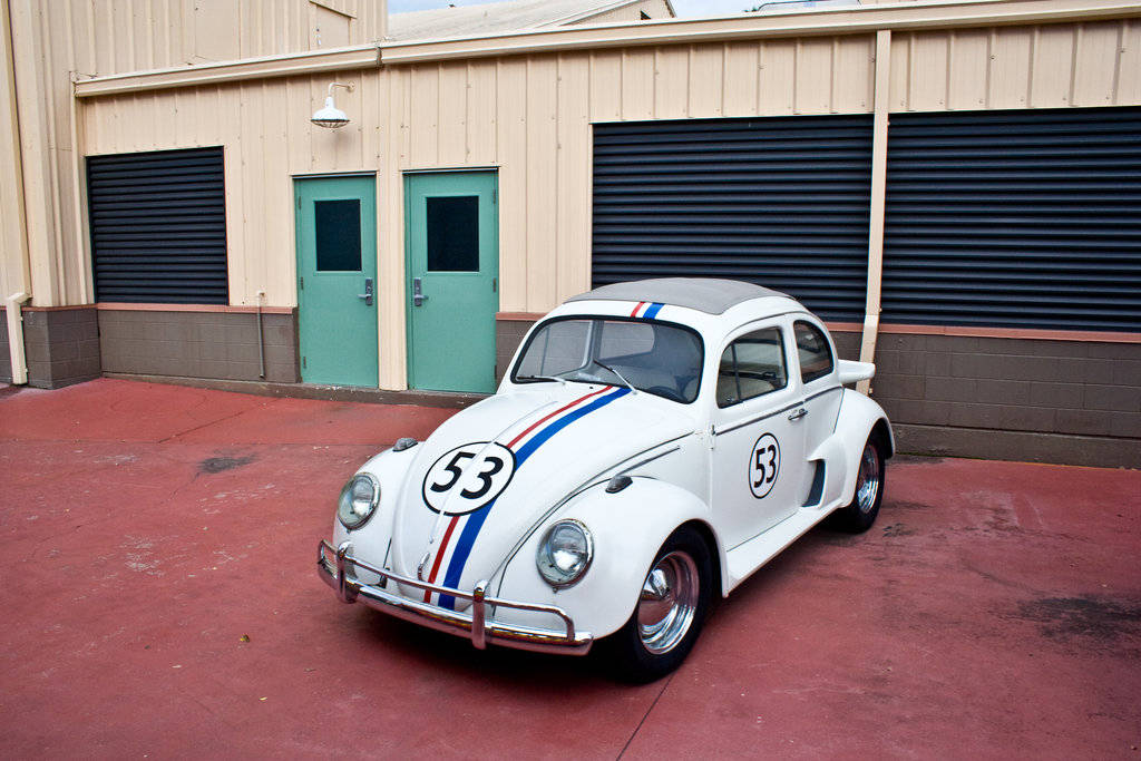 Caption: Herbie the Love Bug parked by a building in the movie 