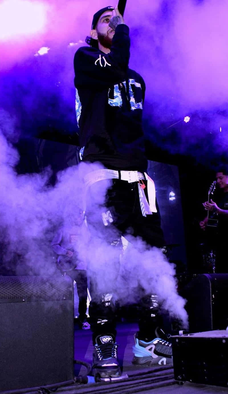 A Man On Stage With Smoke Coming Out Of His Mouth Wallpaper