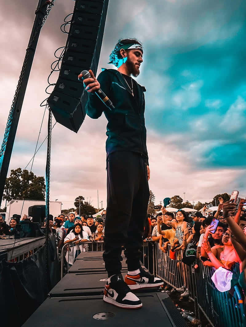 A Man Standing On Stage In Front Of A Crowd Wallpaper