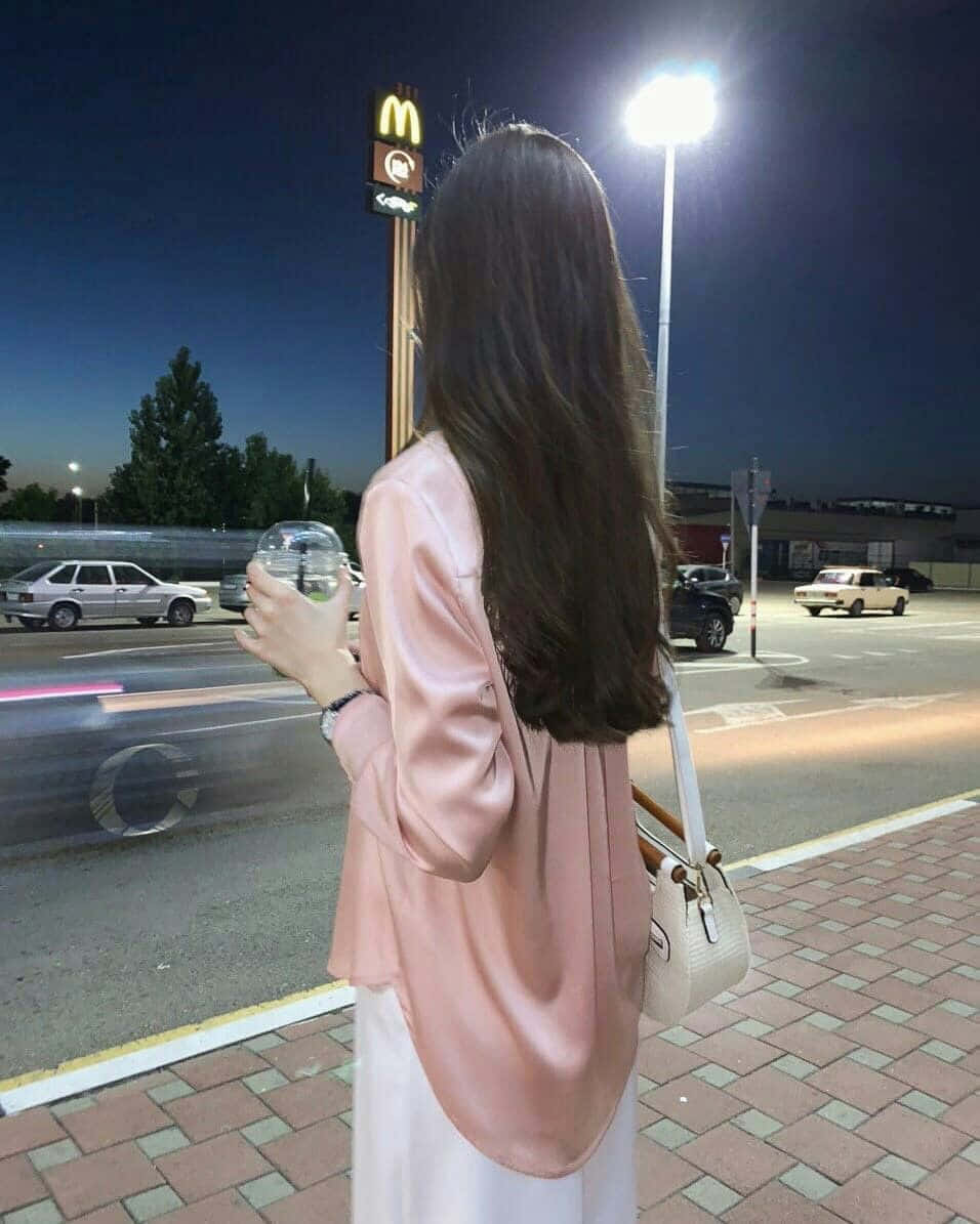 A Woman Is Standing On A Sidewalk At Night