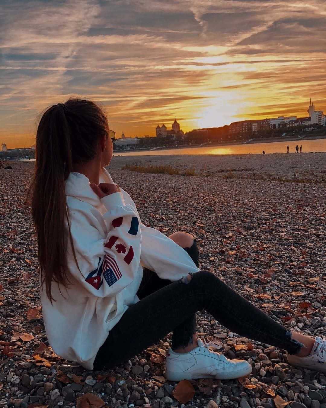 A Girl Sitting On The Beach At Sunset
