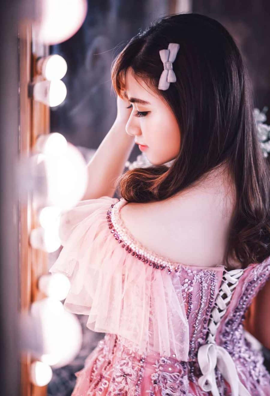A Girl In A Pink Dress Looking At The Mirror