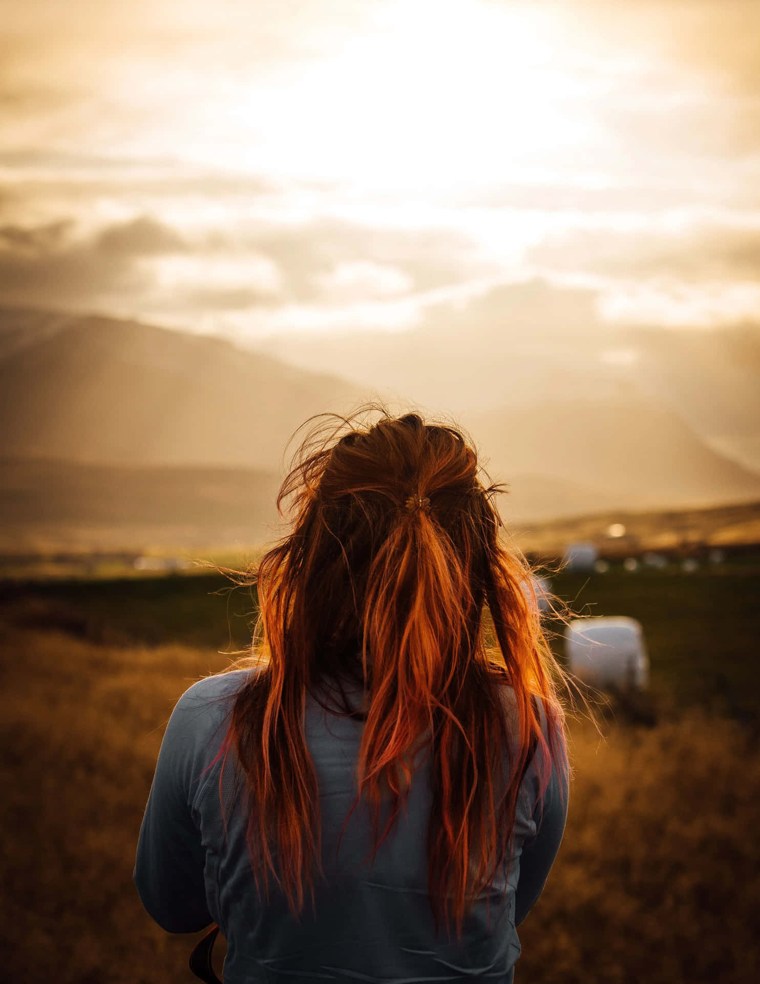 A Woman With Red Hair Looking Out Over A Field
