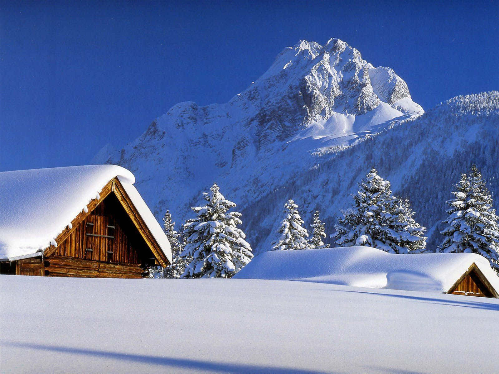 A Snow Covered Mountain With A Cabin In The Background