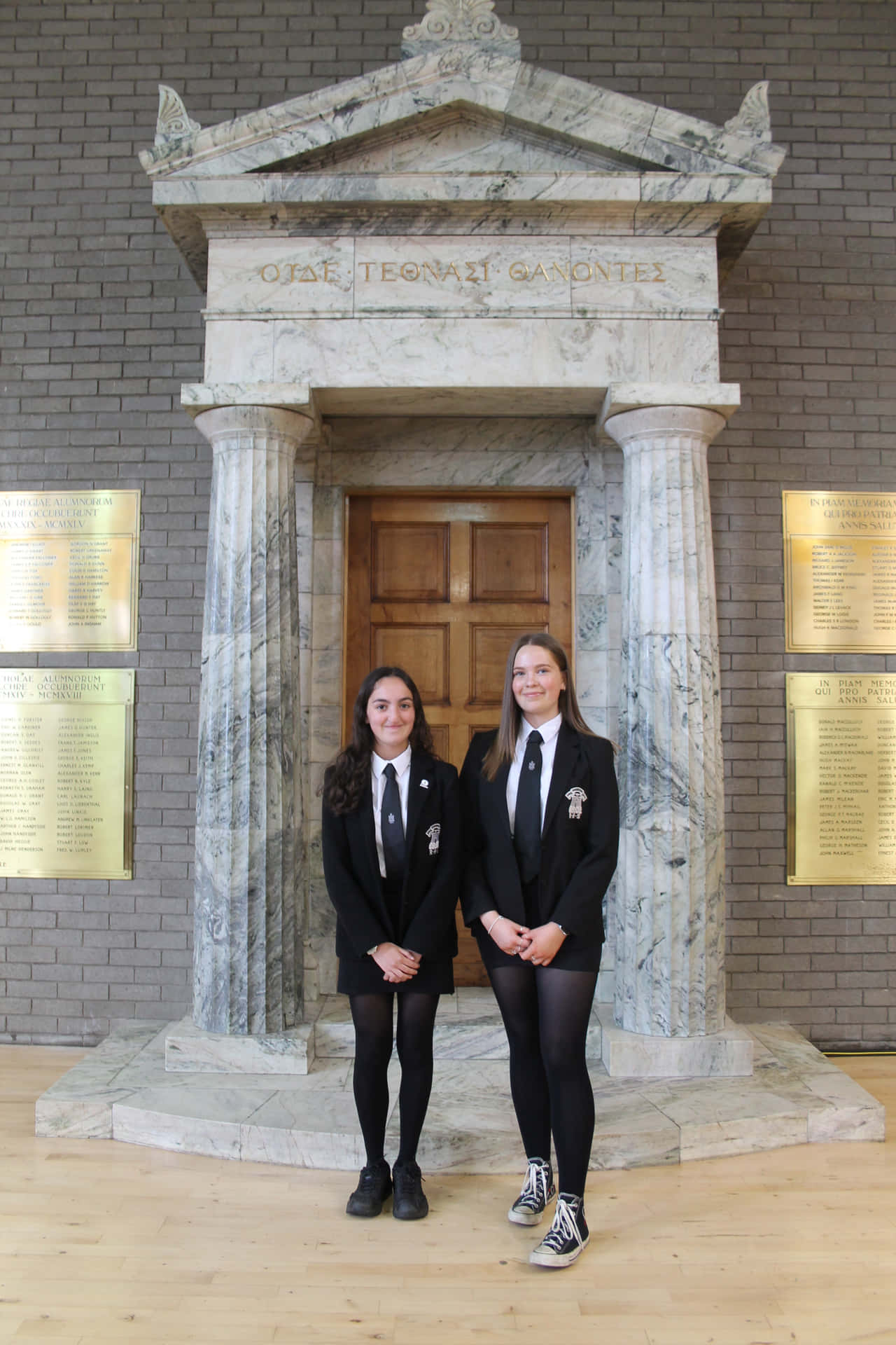 Two Girls Standing In Front Of A Building With A Statue