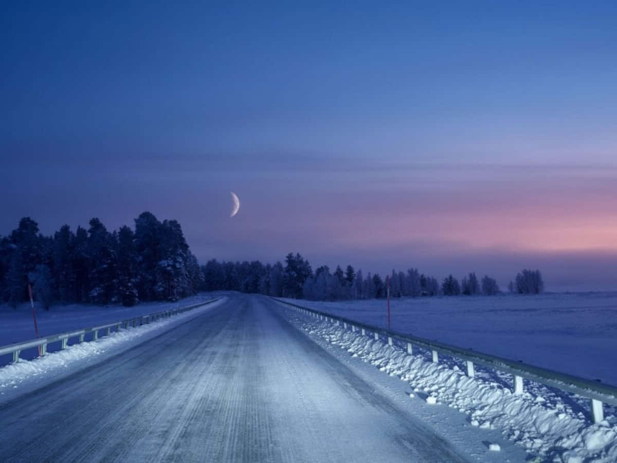 A Road In The Snow With The Moon In The Sky