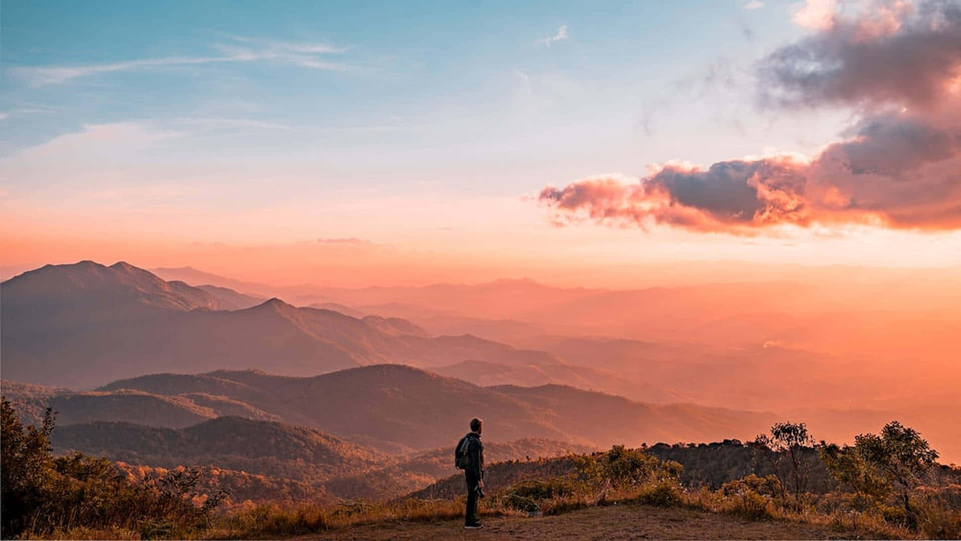 Hiker admiring breathtaking mountain view at sunset