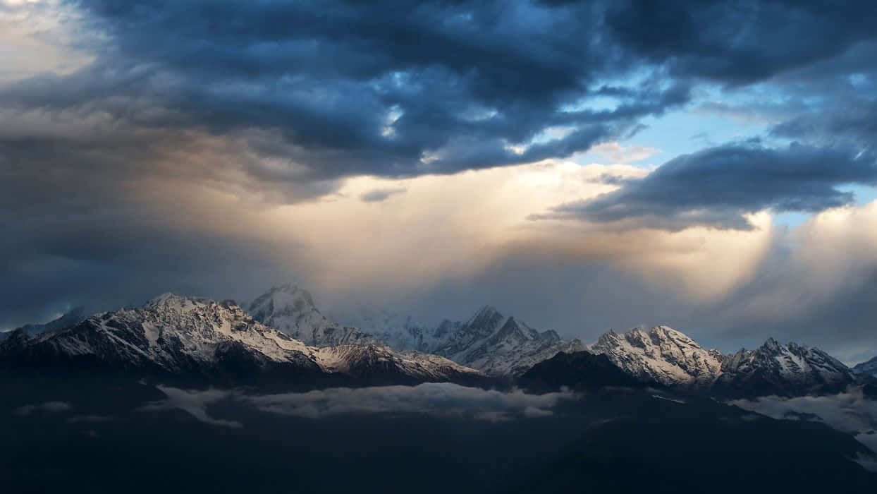 A Cloudy Sky Over Snow Capped Mountains