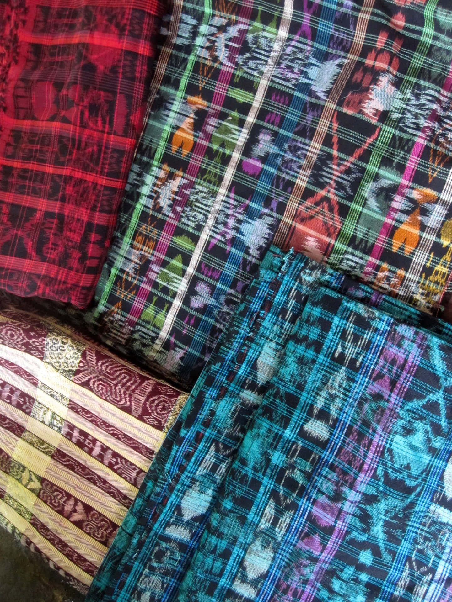 En gruppe af farverige mønstrede tasker er stablet oven på hinanden. Wallpaper