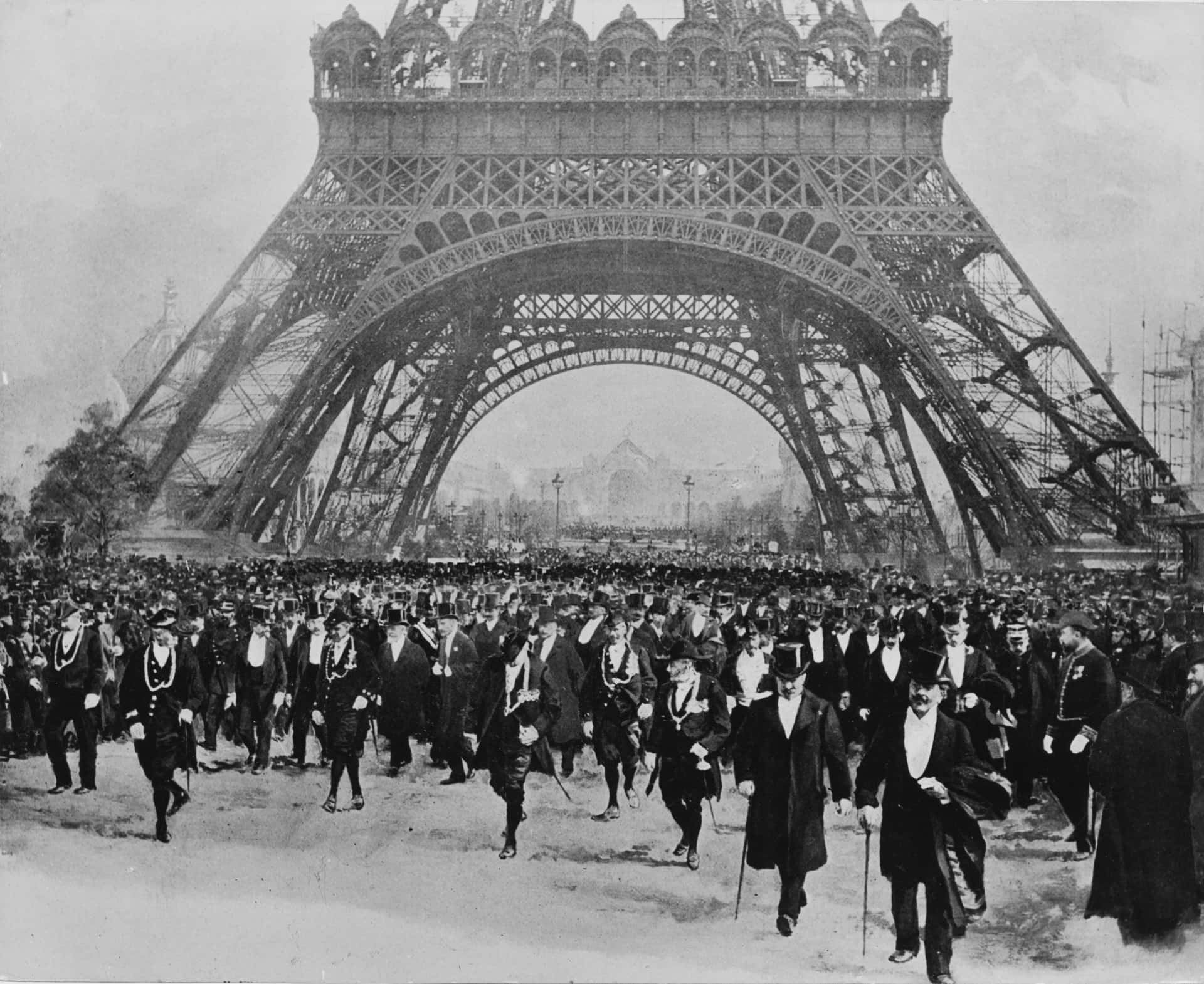 A Group Of People Walking In Front Of The Eiffel Tower