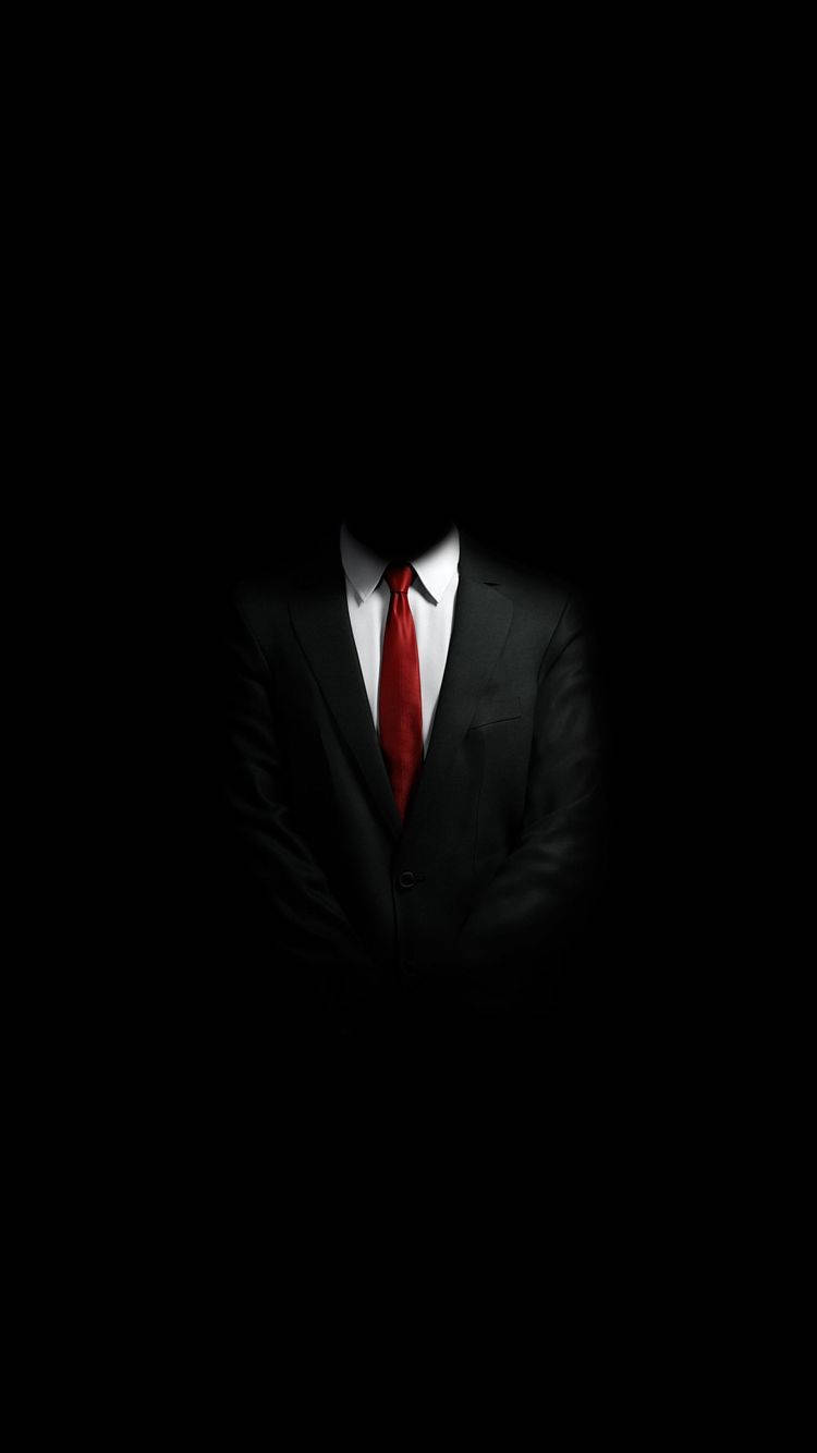 En mand iført jakkesæt og slips står i mørket. Wallpaper
