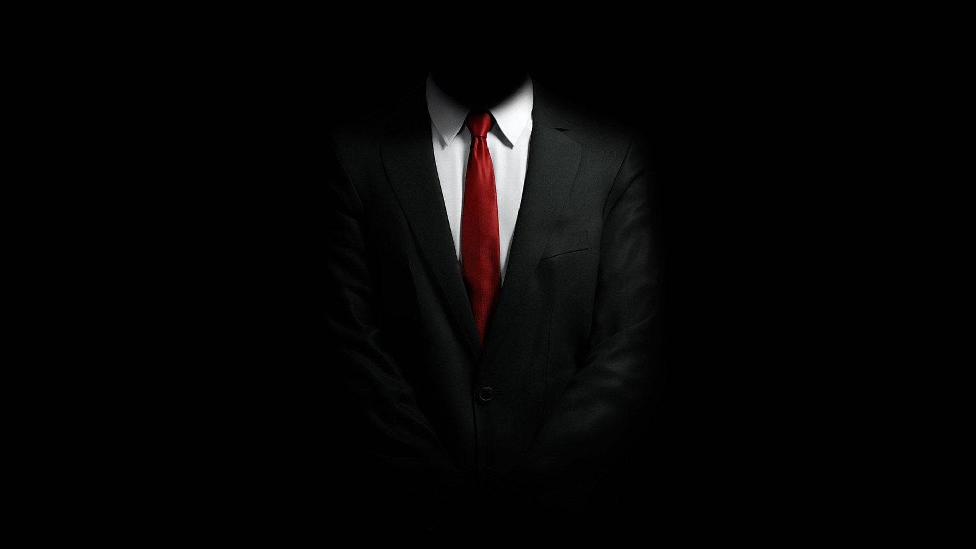 En mand i jakkesæt og slips står i mørket Wallpaper