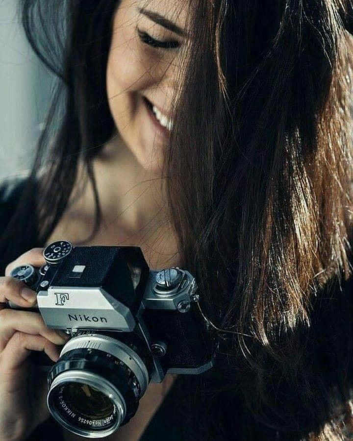 A Woman Smiling While Holding A Camera