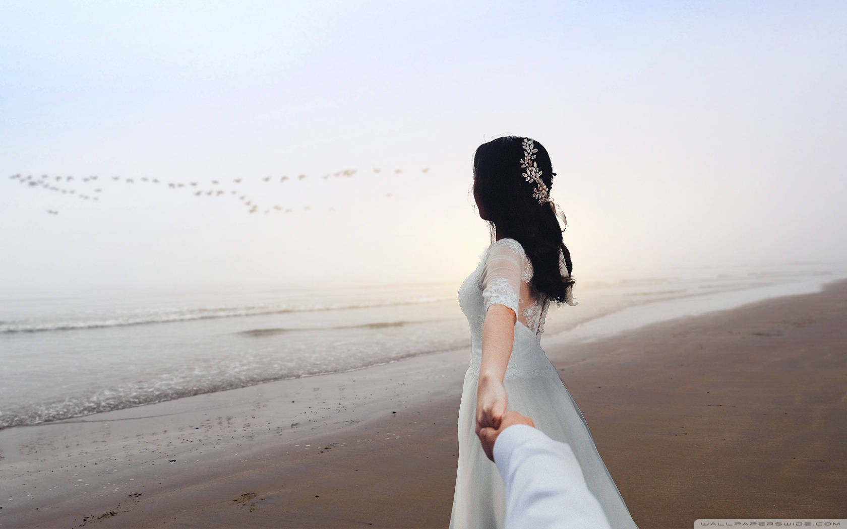 Holding Hands By The Beach In Wedding Gown Wallpaper