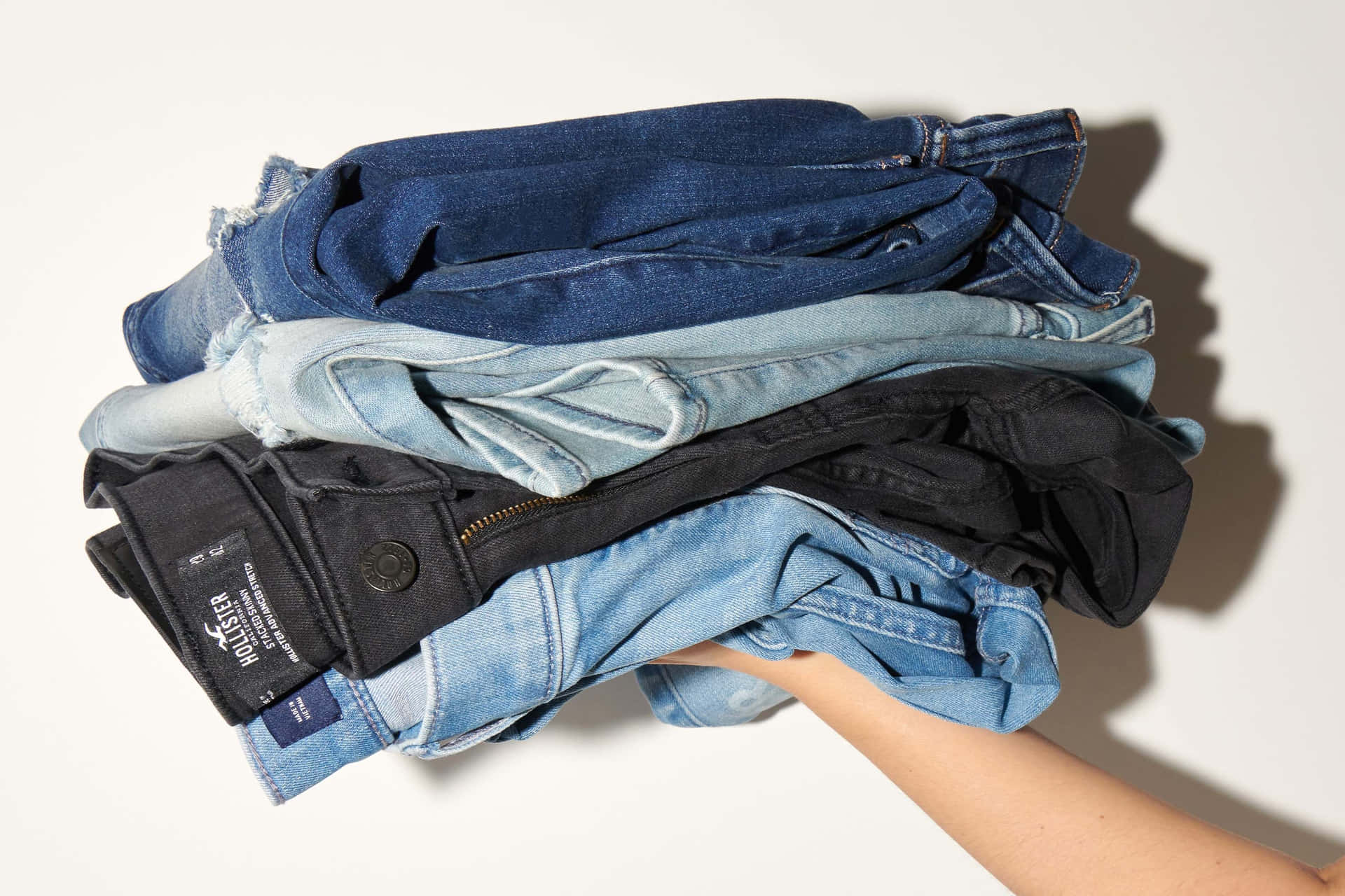 A Woman Holding A Pile Of Jeans