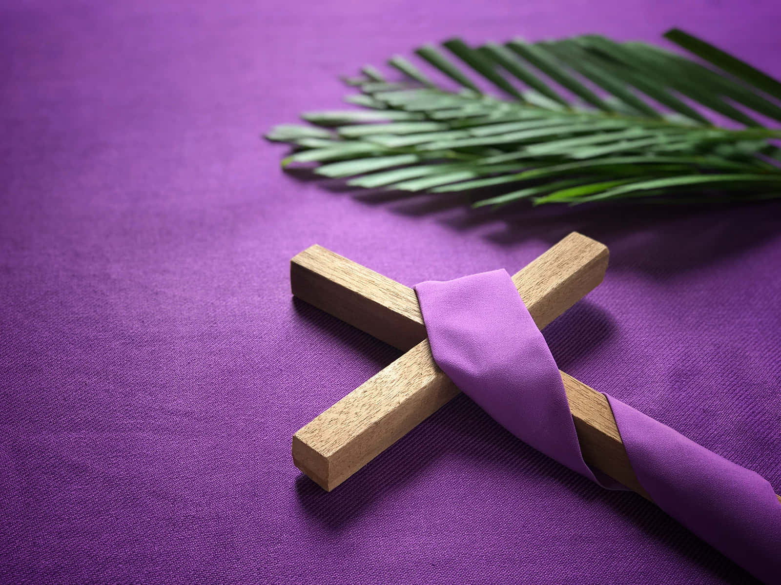A Wooden Cross And Purple Palm Leaves On A Purple Cloth Wallpaper