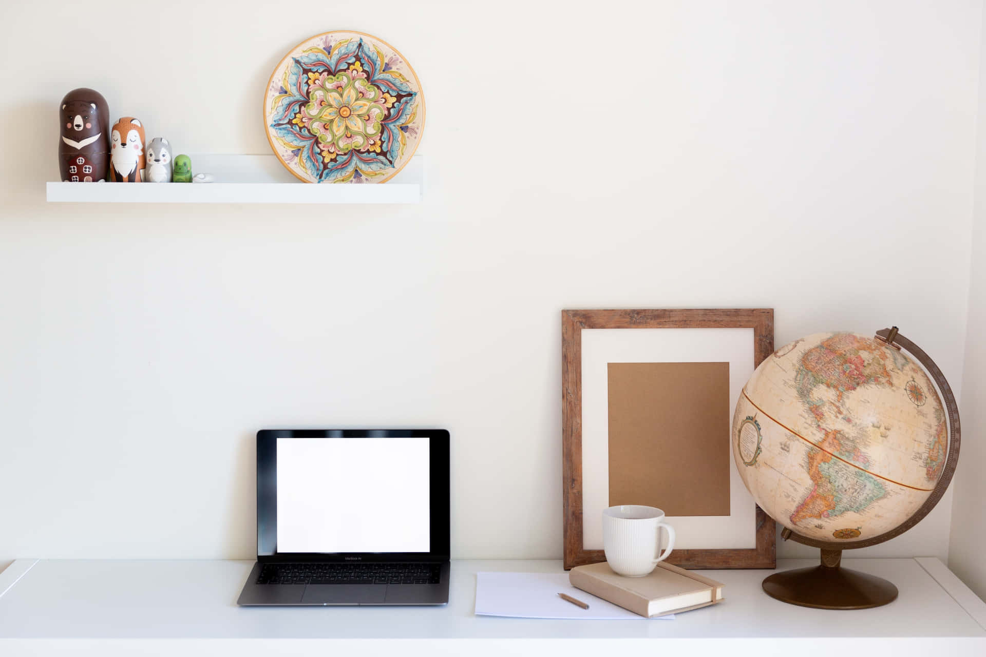 A White Desk With A Laptop, Globe, And A Vase