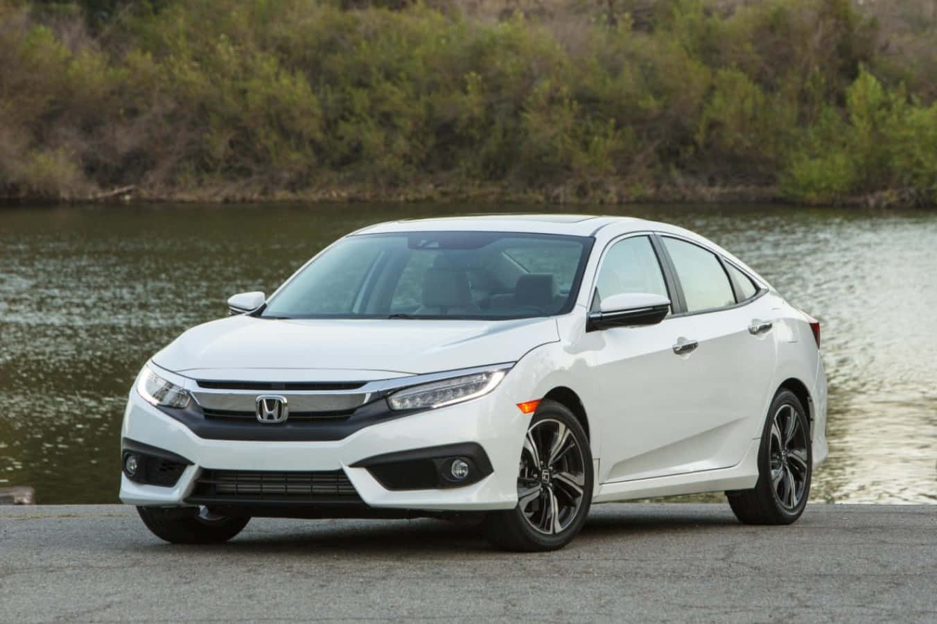 The 2017 Honda Civic Sedan Is Parked In Front Of A Lake