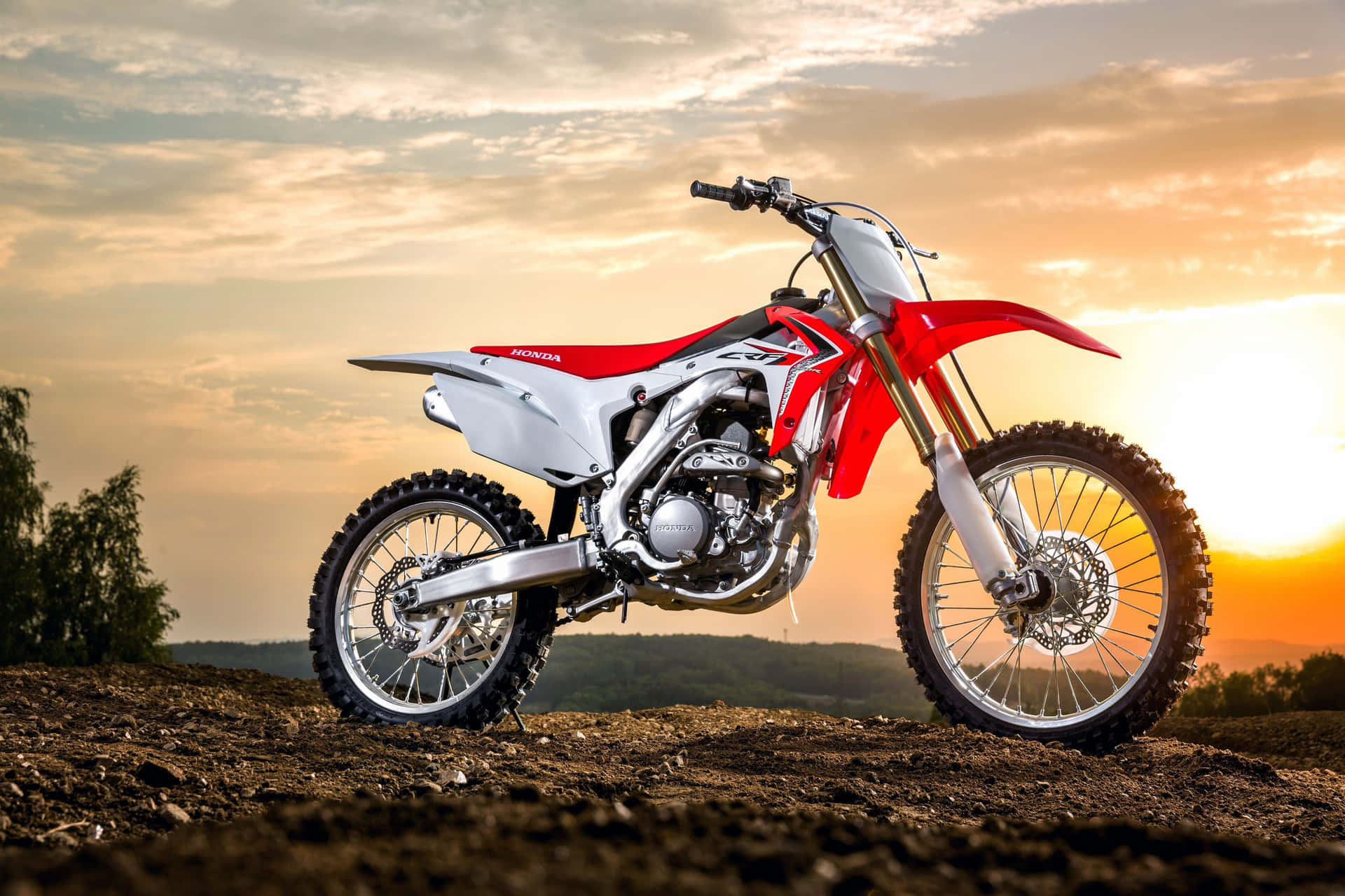 A Red And White Dirt Bike Is Parked On A Dirt Road Wallpaper