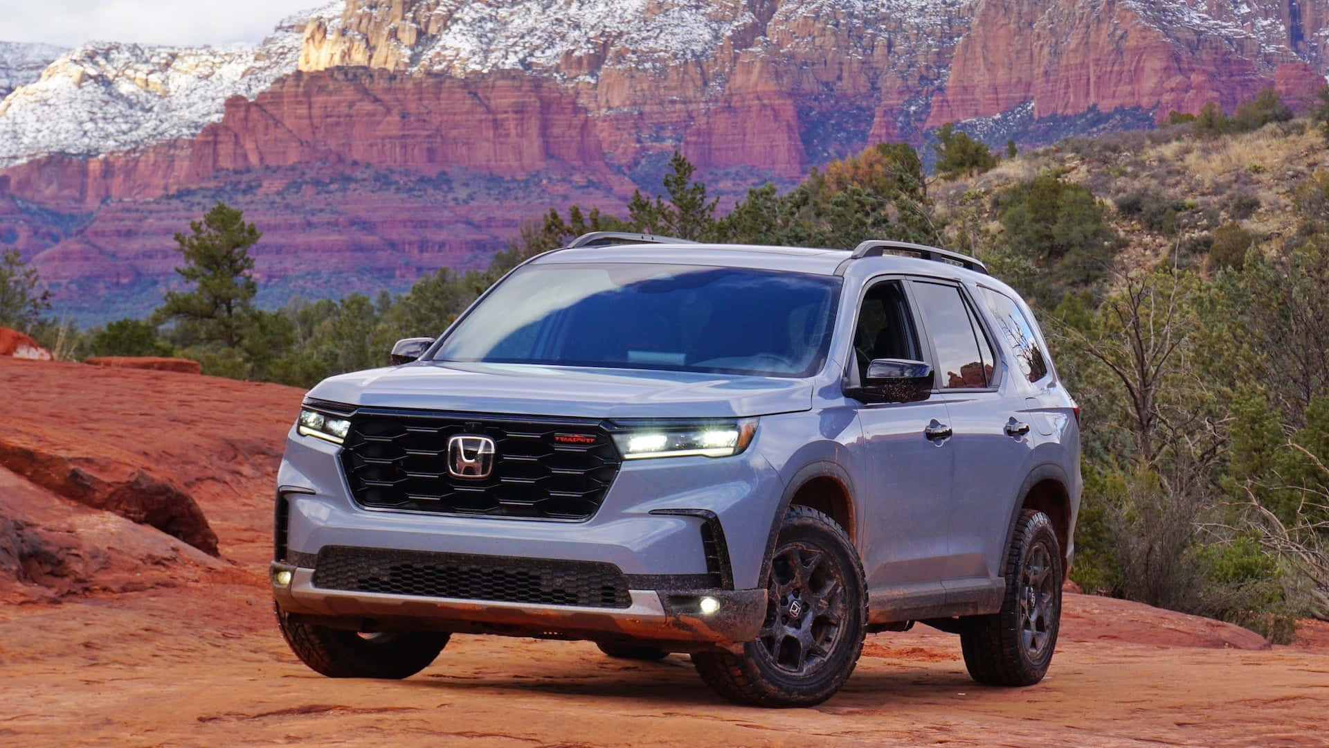 the 2020 honda pilot is driving on a dirt road