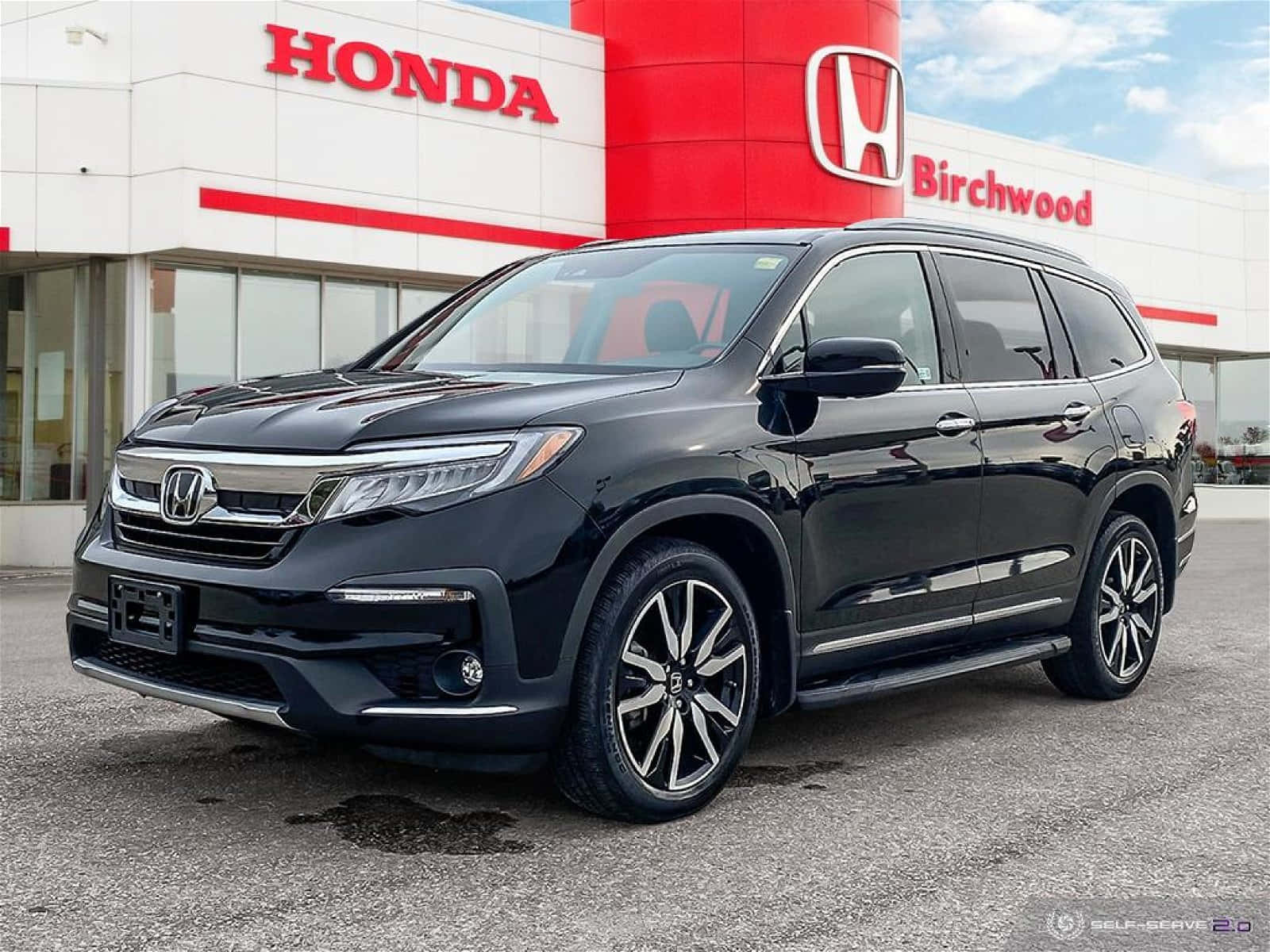 A Black Honda Pilot Is Parked In Front Of A Honda Dealership