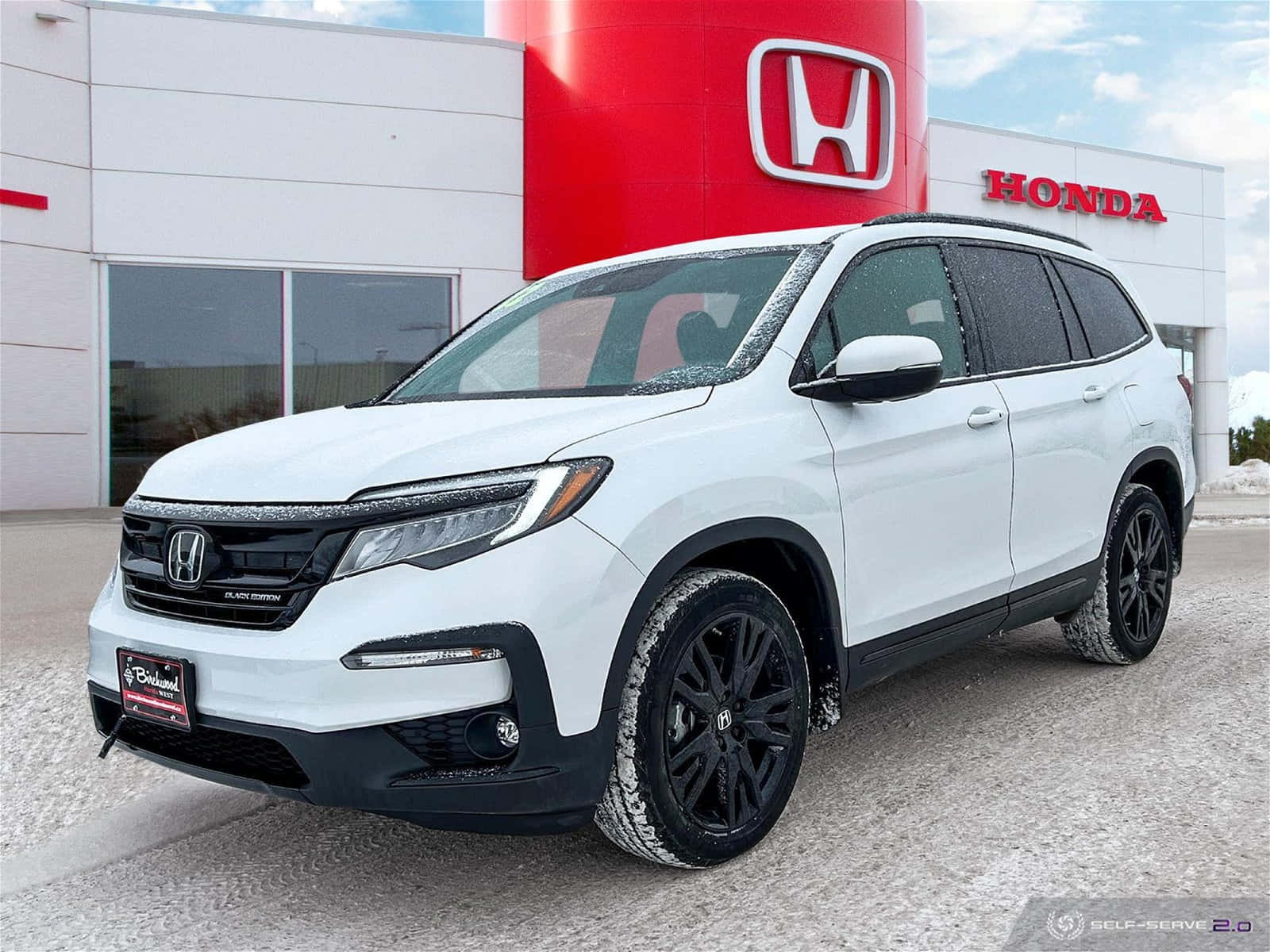 A White 2019 Honda Pilot Is Parked In Front Of A Dealership
