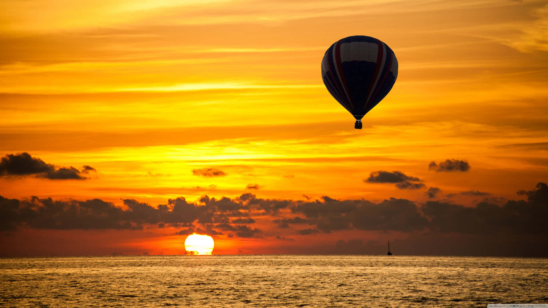 A Hot Air Balloon Flying Over The Ocean At Sunset