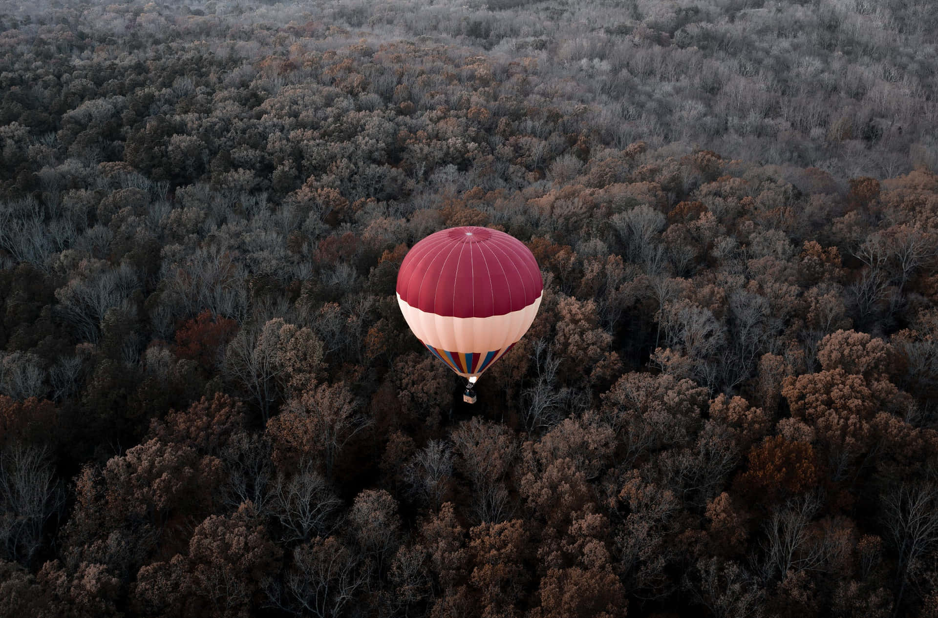 Tethered hot air balloon in front of a majestic mountainside at sunrise