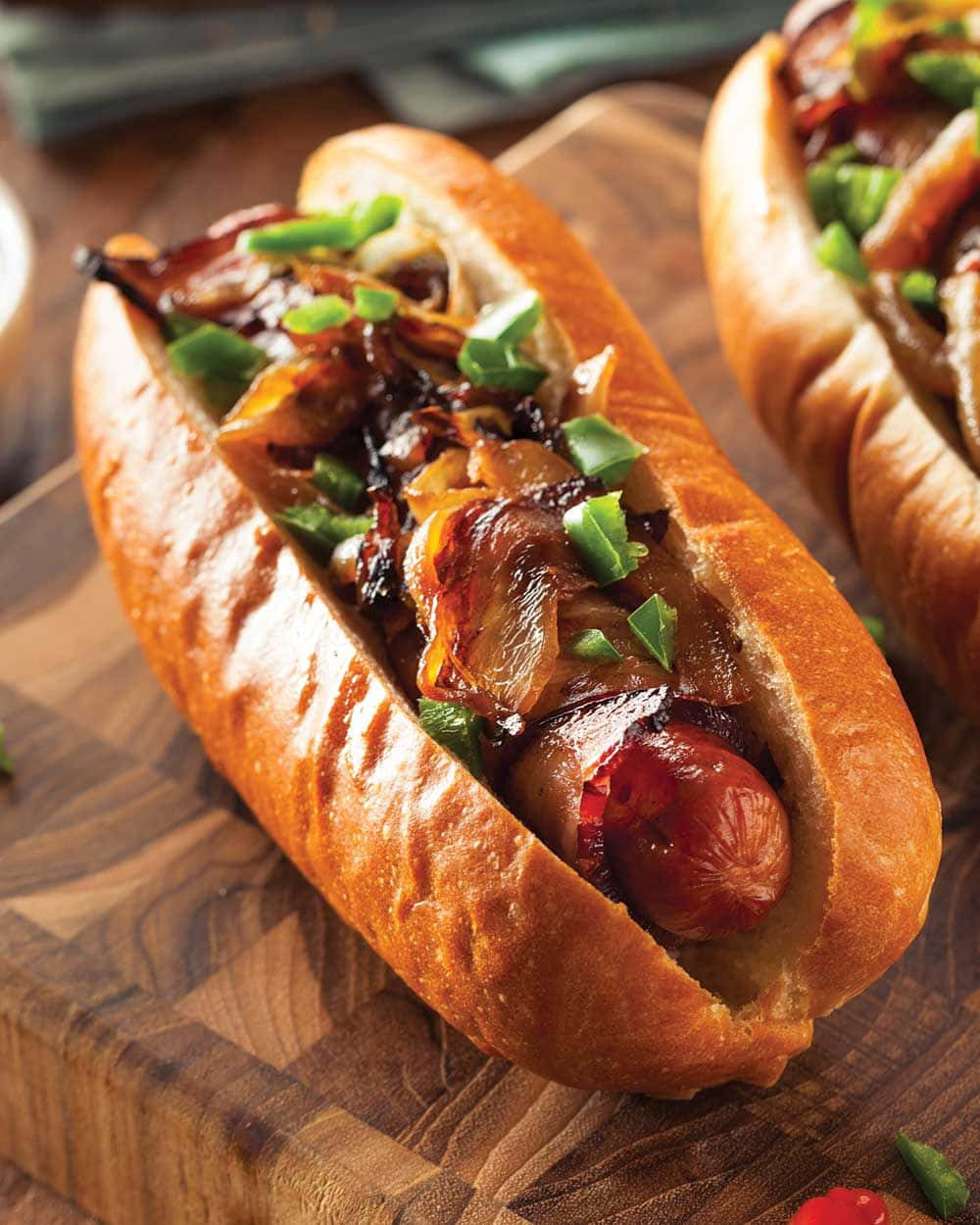 Two Hot Dogs With Onions And Bacon On A Cutting Board