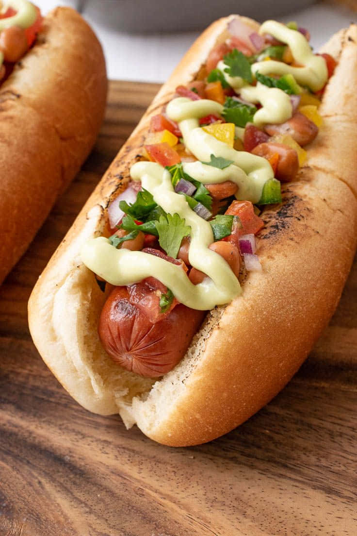 Two Hot Dogs With Toppings On A Wooden Cutting Board